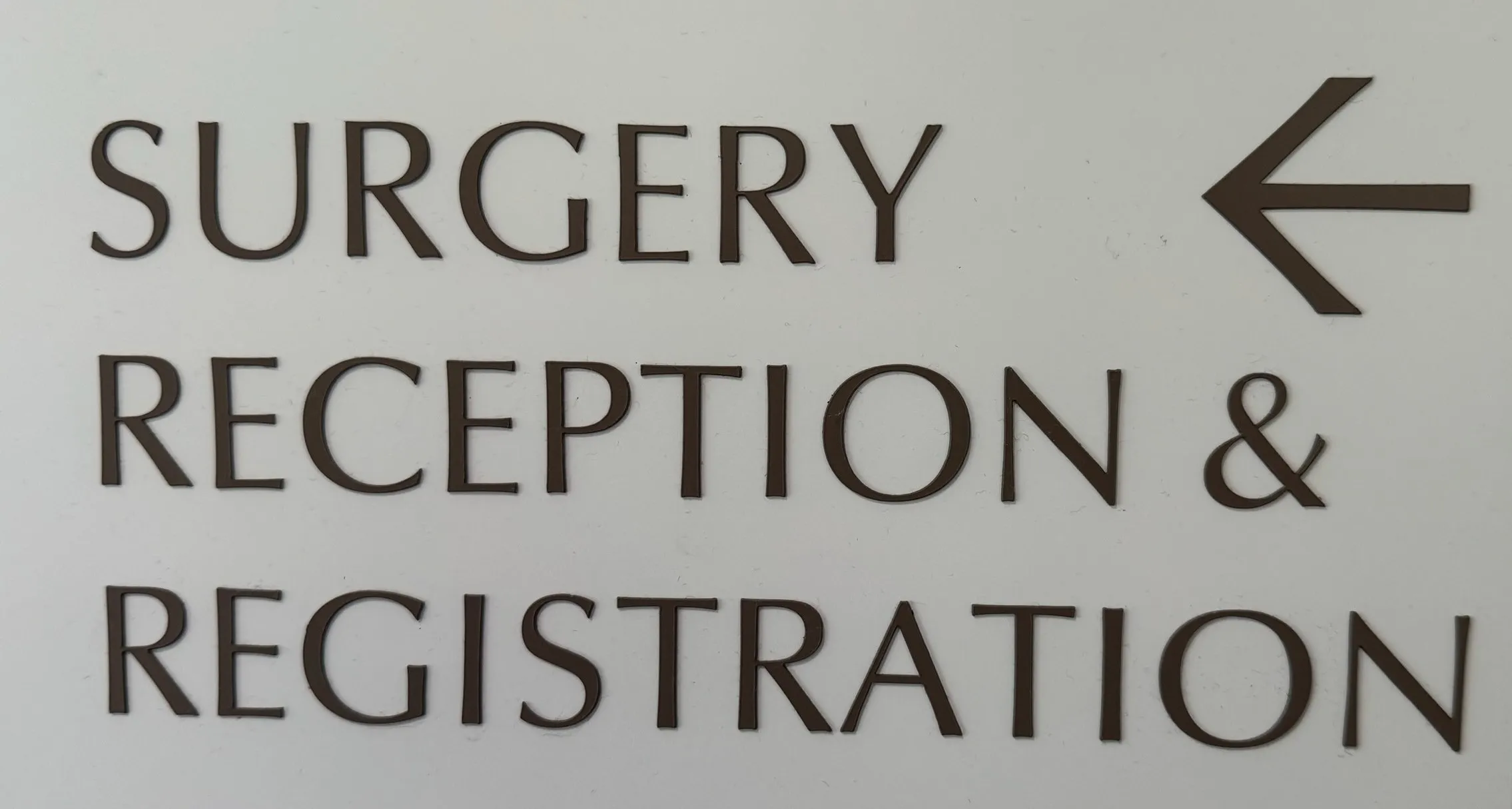 Wayfinding sign with left arrow directing to surgery and reception areas